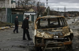 People walks on a street with several dead bodies on the ground a street in Bucha, northwest of Kyiv, as Ukraine says Russian forces are making a "rapid retreat" from northern areas around Kyiv and the city of Chernigiv, on April 2, 2022. -- Photo: Ronaldo Schemidt / AFP