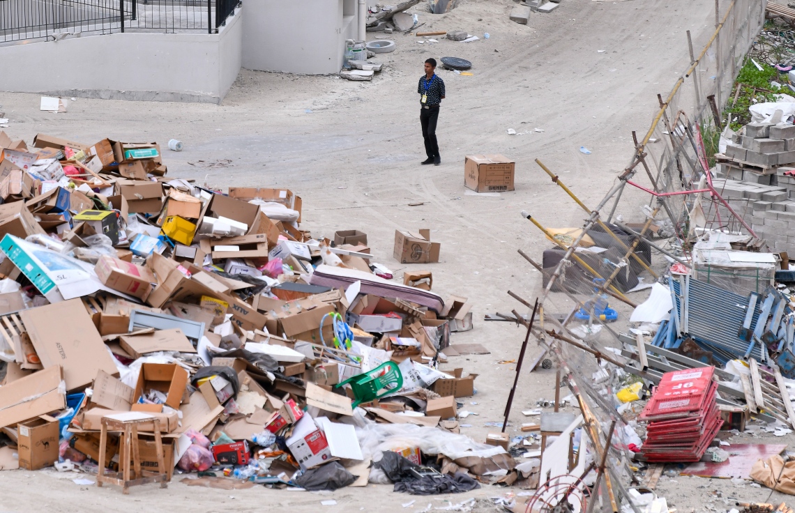 އެޗް 1 އަދި 2 ވަނަ ޓަވަރުގެ މެދަށް ޖަމާކޮށްފައި ހުރި ކުނިތަކެއްގެ ކައިރީގައި އެ ސަރަހައްދުގެ ފްލެޓްތަކުގެ ސެކިއުރިޓީ ބަލަހައްޓާ މީހަކު މަޑުކޮށްލައިގެން.--- ފޮޓޯ: ފަޔާޒު މޫސާ | މިހާރު