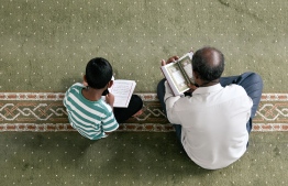 A man reciting the Quran with a child at the Masjid-ul-Jalaluddin. -- Photo: Fayaz Moosa / Mihaaru News