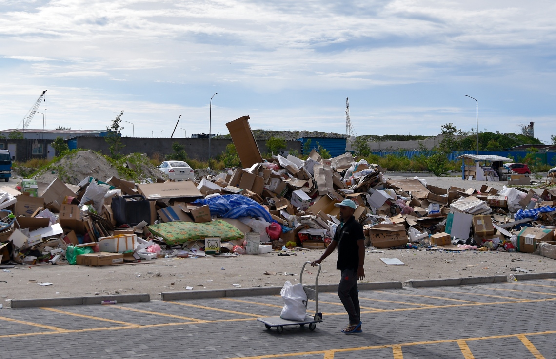 ހިޔާ ފްލެޓް ސަރަހަދަށް ޖަމާކޮށްފައި ހުރި ކުނިތަކެއްގެ ކައިރިން މީހަކު ޓްރޮލީއަކަށް އެއްޗެއް އަރުވައިގެން ދަނީ: ކުނި އުކާލުމުގައި އެއްވެސް ހަމައެއްލަމައެއް ނެތުމުން މި ސަރަހައްދުގެ ނުސާފުތާހިރުކަން ވަރަށް ބޮޑު.--- ފޮޓޯ: ފަޔާޒު މޫސާ | މިހާރު