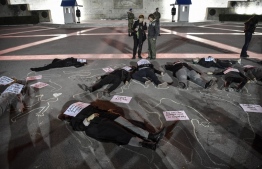 (FILES) In this file photo taken on November 25, 2019, activists lie down in front of the Greek Parliament enlighten in pink, to mark the International Day for the Elimination of Violence against Women, in Athens. - Macho culture has deep roots in the country, and "Greek education, the church and justice are conservative institutions built on the patriarchal model", AFP reports. On average, Greece records 11 femicides per year. -- Photo: Louisa Gouliamaki / AFP