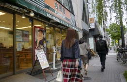 People walks past a Yoshinoya retaurant, which operates a chain of popular beef bowl restaurants in Japan and abroad, in Tokyo on April 19, 2022. - One of Japan's most popular fast food firms said April 19 it had fired a top executive who reportedly suggested a marketing strategy of getting "virgins addicted" to the company's products. -- Photo: Kazuhiro Nogi / AFP