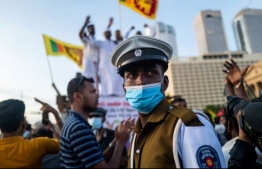 A policeman stands guard as protesters shout slogans during an ongoing anti-government demonstration near the president's office in Colombo on April 18, 2022, demanding President Gotabaya Rajapaksa’s resignation over the country's crippling economic crisis. -- Photo: Jewel Samad / AFP