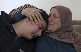 Houria Sabatien, mother of Palestinian woman Ghada Sabatien who was shot by an Israeli soldier on April 10, mourns with her grandchild Mustafa at their home in the village of Husan near Bethlehem in the occupied West Bank on April 18, 2022. . -- Photo: Hazem Bader / AFP