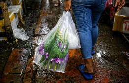 This photo taken on April 12, 2022 shows a customer carrying a bag of orchids at the Pak Khlong Talat wholesale flower market in Bangkok. - Once considered a popular past time among the Thai elite, orchid growing has developed into a multi-million dollar industry and the kingdom is the world's biggest exporter, but the pandemic has seen one in five farms shut recently and growers are expecting further hits due to the war in Ukraine. -- Photo: Lillian Suwanrumpha / AFP