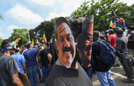 A demonstrator wearing masks of Sri Lanka's President Gotabaya Rajapaksa (R) and Prime Minister Mahinda Rajapaksa takes part in a demonstration with others demanding the resignation of Gotabaya Rajapaksa over the country's crippling economic crisis, near the parliament building in Colombo on May 6, 2022. --Photo: Ishara S. Kodikara / AFP