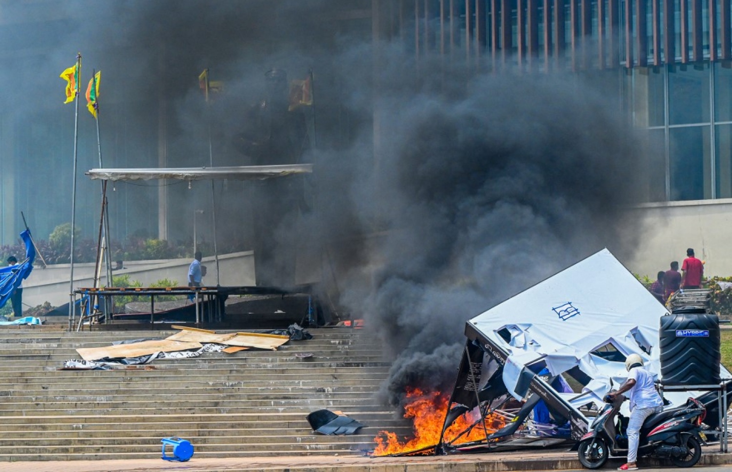 މެއި 9، 2022 - ކޮލަމްބޯ: ސްރީ ލަންކާގައި ހިނގަމުންދާ ހަމަނުޖެހުންތަކުގައި އެ ގައުމުގެ ބޮޑުވަޒީރުގެ ގެކޮޅު ކައިރި ސަރަހައްދެއްގައި ހުރި ކިއޮސްކެއްގައި ރޯކޮށްލާފައި. -- ފޮޓޯ: އޭއެފްޕީ