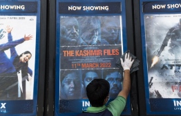 (FILES) In this file photo taken on April 7, 2022, a worker cleans a display with the poster of the Bollywood movie 'The Kashmir Files', outside a cinema hall in New Delhi. - Singapore has banned a controversial Indian film over its "provocative and one-sided portrayal" of Muslims in Kashmir that officials fear could provoke religious and ethnic tensions in the city-state. -- Photo:  Xavier Galiana / AFP