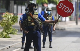 (FILE) A navy soldier holds a stop sign at a road checkpoint in Colombo on May 11, 2022.: according to the police  four civilians and three soldiers were wounded when the army opened fire in an attempt to control the unrest in Sri Lanka in response to fuel shortages -- Photo: Ishara S. Kodikara / AFP
