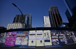View of a fence with photos of missing persons from the Glorieta de la Palma on Paseo de la Reforma Avenue, after relatives and members of search groups proposed to rename it 'Glorieta de Las y Los Desaparecidos' (Roundabout of the Disappeared), in Mexico City, on May 17, 2022. - The number of people reported missing in violence-wracked Mexico has exceeded 100,000, according to official data, with rights groups calling for "immediate" action from the government to locate the disappeared. -- Photo: Pedro Pardo / AFP