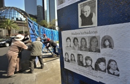 Workers of Mexico's City government move a fence with photos of missing persons from the Glorieta de la Palma on Paseo de la Reforma Avenue, after relatives and members of search groups proposed to rename it 'Glorieta de Las y Los Desaparecidos' (Roundabout of the Disappeared), in Mexico City, on May 17, 2022. - The number of people reported missing in violence-wracked Mexico has exceeded 100,000, according to official data, with rights groups calling for "immediate" action from the government to locate the disappeared. -- Photo: Pedro Pardo / AFP