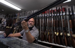 (FILES) In this file photo taken on October 01, 2020 salesman Paul Fraker shows off weapons for sale at Coliseum Gun Traders Ltd. in Uniondale, New York. - US firearms makers produced over 139 million guns for the commercial market over the two decades from 2000, including 11.3 million in 2020 alone, according to a new government report -- Photo: Timothy A. Clary / AFP