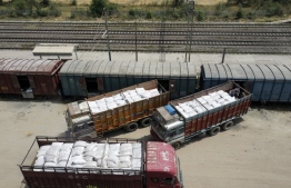 This aerial photograph shows workers loading sacks of wheat from trucks to a freight train at Chawa Pail railway station in Khanna, Punjab state, on May 19, 2022. - India, the world's second-largest producer of wheat, on May 14 announced it would ban exports without special authorisation from the government in the face of falling production caused primarily by an extreme heatwave. -- Photo: Sajjad Hussain/ AFP