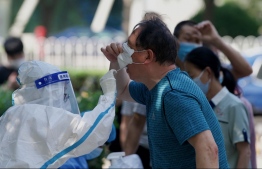 A health worker takes a swab sample from a man to be tested for the Covid-19 coronavirus at a swab collection site in Beijing on May 23, 2022. -- Photo: Noel Celis / AFP