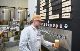 A worker pours a pint of beer at Pressure Drop Brewery, in north London, on May 21, 2022. - Members of staff at the Pressure Drop brewery are taking part in a six-month trial of a four-day working week, with 3,000 others from 60 UK companies. The pilot -- touted as the world's biggest so far -- aims to help companies shorten their working hours without cutting salaries or sacrificing revenues. -- Photo: Justin Tallis / AFP
