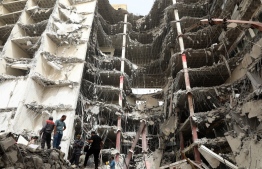 Iranians gather at the site where a ten-storey building collapsed as rescue operations continue in the southwestern city of Abadan on May 24, 2022. - At least six people died and dozens were injured or missing under rubble after an unfinished high-rise building collapsed in southwestern Iran, officials said. -- Photo: Tasnim News / AFP