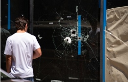 A pedestrian walks past bullet holes in the window of a store front on South Street in Philadelphia, Pennsylvania, on June 5, 2022. -- Photo: Kriston Jae Bethel / AFP