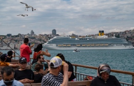 Bystanders watch a Costa Venezia cruise ship in Galataport Istanbul, on June 06, 2022. - Galataport, located in Istanbul's neighborhood of Karakoy, is set to energise cruise tourism from the Mediterranean Sea to the Black Sea amidst Turkish economy tailspin over a weakening lira currency and soaring inflation. -- Photo: Yasin Akgul / AFP