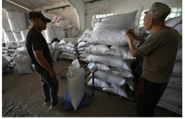 Farm workers stack bags of sunflowers seeds in a storage at a farm in the southern Ukraine’s Mykolaiv region, on June 11, 2022, amid the Russian invasion of Ukraine. Located not far from the city of Mykolaiv, a farm were shelled last March when the Russians tried to advance north, killing only two peacocks that usually ruled the barnyard. -- Photo: Genya Savilov / AFP