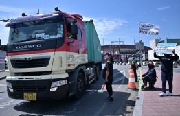 A South Korean truck driver (L) leaving a container port is asked to join striking drivers in Incheon on June 14, 2022, on the eighth day of protests over rising fuel costs that have further snarled global supply chains. -- Photo: Anthony Wallace / AFP
