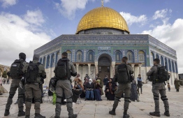 އަގްސާ މިސްކިތުގެ ބޭރުގައި މުސްލިމުންތަކެއް ހިފަހައްޓައިގެން އިޒްރޭލުގެ ސިފައިން ހަތިޔާރާ އެކު ބިރު ދައްކަނީ.