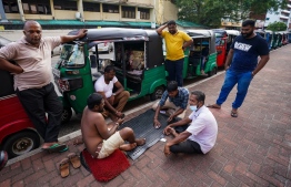 Autorickshaw drivers play a cards game while queueing to buy petrol from a Ceylon petroleum corporation fuel station in Colombo on June 18, 2022. -- Photo: AFP