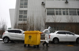 (FILES) In this file photo taken on February 14, 2020, a worker carts a bin loaded with medical waste at the Youan Hospital in Beijing. - Hazmat-suited workers poke plastic swabs down millions of throats in China each day, leaving bins bursting with medical waste that has become the environmental and economic levy of a zero-Covid strategy. -- Photo: Greg Baker / AFP