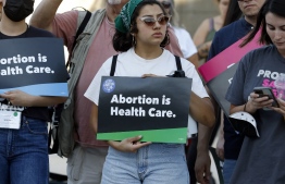 A woman holds a "Abortion is Health Care" sign as abortion rights activists rally outside the Lloyd D. George Federal Courthouse in protest of the overturning of Roe Vs. Wade by the US Supreme Court, in Las Vegas, Nevada on June 24, 2022. - The US Supreme Court on Friday struck down the right to abortion in a seismic ruling that shredded five decades of constitutional protections and prompted several right-leaning states to impose immediate bans on the procedure. -- Photo: Ronda Churchill / AFP