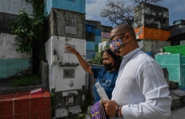 This photo taken on June 10, 2022 shows Gemma Baran (L) walking with Father Flavie Villanueva (R) -- a priest who has received death threats and been charged with sedition for his criticism of President Rodrigo Duterte's bloody drug war -- during work to exhume the remains of victims of the drug war at Tala Cemetery in Caloocan, Metro Manila. - Official data show more than 6,200 people have died in police anti-narcotics operations since outgoing-Philippine President Rodrigo Duterte was swept to power in 2016 promising to rid the country of drugs. -- Photo: Jam Sta Rosa / AFP