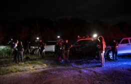 News reporters stand near the scene where a tractor-trailer was discovered with migrants inside outside San Antonio, Texas on June 27, 2022. - At least 46 migrants were found dead June 27, 2022 in and around a tractor-trailer that was abandoned on the roadside on the outskirts of the Texas city of San Antonio. -- Photo: Sergio Flores / AFP