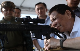 (FILES) This file handout photo taken and released by the Presidential Photo Division (PPD) on March 1, 2018 shows President Rodrigo Duterte (R) firing a few rounds with a sniper rifle during the opening ceremony of the National Special Weapons and Tactics (SWAT) Challenge in Davao City on the southern Philippine island of Mindanao. Philippine President Rodrigo Duterte has been accused of rights abuses in a drug war that has killed thousands of people. But analysts say he is unlikely to face charges after he steps down on June 30, 2022. -- Robinson Niñal / Presidential Photo Division / AFP