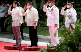 Incoming Philippine President Ferdinand Marcos Jr (L) and outgoing President Rodrigo Duterte (2nd L) salute during the inauguration ceremony for Marcos at the Malacanang presidential palace grounds in Manila on June 30, 2022. - The son of the Philippines' late dictator Ferdinand Marcos was to be sworn in as president on June 30, completing a decades-long effort to restore the clan to the country's highest office. (Photo by Francis R. MALASIG / POOL / AFP)