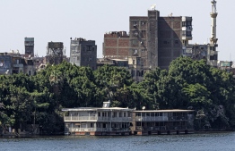 This picture taken on June 27, 2022 from the Cairo side of the Nile river shows houseboats moored along the Giza bank in the Agouza district, days before their expected removal as part of a wider decree to clear all of the river's banks in the area. -- Photo: Khaled Desouki / AFP