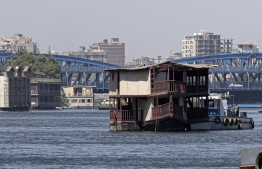 One of the houseboats usually moored across one of the banks of the Nile river between the Zamalek district of Egypt's capital Cairo (R) and the Agouza district of its twin city of Giza (L) is towed away by authorities on June 27, 2022, as part of a wider decree to clear all of the river's banks in the area. --Photo: Khaled Desouki / AFP