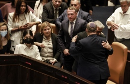 Israeli Minister of Foreign Affairs Yair Lapid (2-R) and outgoing Prime Minister Naftali Bennett, embrace each other at the Knesset (parliament), following the dissolution of the parliament, in Jerusalem on June 30, 2022. -- Photo by Menahem Kahana / AFP