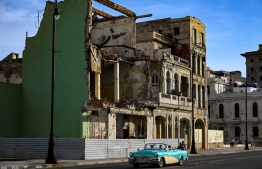 An old American car drives by a building at risk of collapse in Havana, on June 23, 2022. - Collapses occur with some frequency in the Cuban capital, especially in the old part of the city, where the old buildings suffer great deterioration and overcrowding. The danger increases during the Atlantic hurricane season, which runs from June 1 to November 30. -- Photo: Yamil Lage / AFP