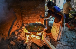 In this picture taken on March 15, 2022, a woman uses firewood to cook food at a hotel in Colombo. - As once relatively wealthy Sri Lanka suffers a dire economic crisis with shortages of everything from medicines to gas, locals are returning to cooking with firewood. (Photo by Ishara S. KODIKARA / AFP) / 