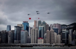 Helicopters fly past with the Hong Kong and Chinese flags during a flag-raising ceremony to celebrate the 25th anniversary of the city's handover from Britain to China, in Hong Kong on July 1, 2022. - President Xi Jinping hailed China's rule over Hong Kong as he lead 25th anniversary celebrations of the city's handover from Britain on July 1, insisting that democracy is flourishing despite a years-long political crackdown that has silenced dissent. -- Photo: Isaac Lawrence / AFP