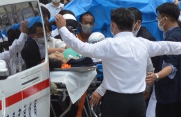 Former Japanese prime minister Shinzo Abe (C) is transported into an ambulance near Yamato Saidaiji Station after being shot in the city of Nara on July 8, 2022.  (Photo by Yomiuri Shimbun / AFP) /
