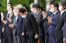 Japan's Prime Minister Fumio Kishida, officials and employees offer prayers as a hearse transporting the body of former prime minister Shinzo Abe makes a brief visit to the Prime Minister's Office after the funeral ceremony in Tokyo on July 12, 2022. -- Photo: Eugene Hoshiko / POOL / AFP