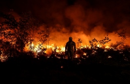 A tactical firefighter set fires to burn a plot of land as firefighters attempt to prevent the wild fire from spreading due to wind change, as they fight a forest fire near Louchats in Gironde, southwestern France on July 17, 2022. - France was on high alert on July 18, 2022, as the peak of a punishing heatwave gripped the country, while wildfires raging in parts of southwest Europe showed no sign of abating. In the southwestern Gironde region, firefighters over the weekend continued to fight to control forest blazes that have devoured nearly 11,000 hectares (27,000 acres) since July 12. -- Photo: Thibaud Moritz  / AFP