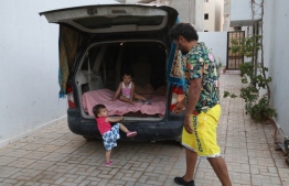 Mahmud Aguil sits with his children in the back of his air-conditioned van, parked at his home in Libya's capital Tripoli, on July 5, 2022. - Aguil, 48, who has a comfortable house in central Tripoli, has been forced to sleep with his two children in the back of his air-conditioned van amid enduring power cuts of up to 18 hours a day, the latest trial for Libyans after a decade of persistent insecurity, fuel shortages, crumbling infrastructure and economic woes since the 2011 NATO-backed uprising that toppled and killed dictator Moamer Kadhafi. -- Photo: Mahmud Turkia / AFP