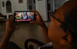 A man a watches a live broadcast of the swearing-in ceremony of Sri Lanka's president-elect Ranil Wickremesinghe on a mobile phone in Galle on July 21, 2022. - Sri Lanka's six-time prime minister Ranil Wickremesinghe was set to be sworn in as president on July 21, with officials saying he would set up an all-party unity cabinet to confront the country's economic crisis. -- Photo: Ishara Kodikara / AFP