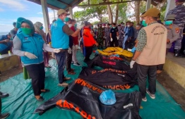 This handout picture taken and released on July 21, 2022 by Indonesia's National Search And Rescue Agency (BASARNAS) shows a rescue team next to victim's bodies after a ferry sank in bad weather in waters off Indonesia's Ternate island. - The KM Cahaya Arafah capsized in waters off Indonesia's Ternate island on July 18, prompting a search and rescue operation for 13 missing people. -- Photo: Handout / Basarnas / AFP