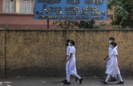 In this picture taken on July 19, 2022, nurses walk outside the National Hospital in Colombo. - Entire wards are dark and nearly empty in Sri Lanka's largest hospital, its few remaining patients leaving untreated and still in pain, and doctors prevented from even arriving for their shifts. An unprecedented economic crisis has dealt a body blow to a free and universal healthcare system that just months earlier was the envy of the country's South Asian neighbours. -- Photo: AFP