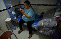 This photo taken on May 9, 2022 shows Peruvian national Zoila Lecarnaque Saavedra, recently released after serving time in prison for drug trafficking and now awaiting deportation, using her phone in a cramped hostel in Hong Kong. - Zoila Lecarnaque Saavedra sealed her fate when she agreed to transport a package from Peru to Hong Kong -- a decision that landed her more than eight years in prison. A quarter of Hong Kong's prisoners are women, a record-high percentage skewed by impoverished foreign drug mules who are often duped or coerced. -- Photo: Peter Parks / AFP
