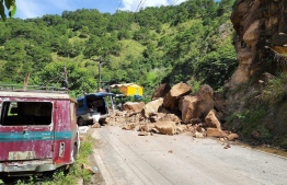 This handout photo taken and released on July 27, 2022 by the Mountain Province Disaster Risk Reduction Management Office shows boulders and a damaged vehicle (C) blocking a road following a landslide along Halsema Highway in the municipality of Bontoc, Mountain Province, after a 7.0-magnitude earthquake hit the northern Philippines. -- Photo by Handout / Mountain Province Disaster Risk Reduction Management Office / AFP