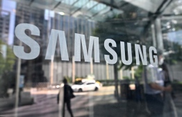 People walk past the Samsung logo displayed on a glass door at the company's Seocho building in Seoul on July 28, 2022. -- Photo: Jung Yeon-je / AFP