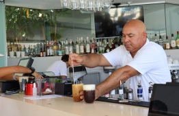 A bartender works at the Alion Beach Hotel in the Cypriot resort town of Ayia Napa, one of the Mediterranean island's top tourist destinations, on July 21, 2022. - Beside sparkling Mediterranean waters at the Cypriot resort town of Ayia Napa, the bars are bouncing with foam dance parties as tourist numbers rebound following two tough years of pandemic. But one key nationality is effectively missing: Russian visitors, as the once lucrative market has been hit by European Union sanctions imposed after Moscow invaded Ukraine. (Photo by Etienne TORBEY / AFP)
