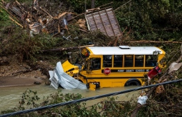 A Perry County school bus, along with other debris, sits in a creek near Jackson, Kentucky, on July 31, 2022. - Rescuers in Kentucky are taking the search effort door-to-door in worsening weather conditions as they brace for a long and grueling effort to locate victims of flooding that devastated the state's east, its governor said on July 31, 2022. -- Photo: Seth Herald / AFP